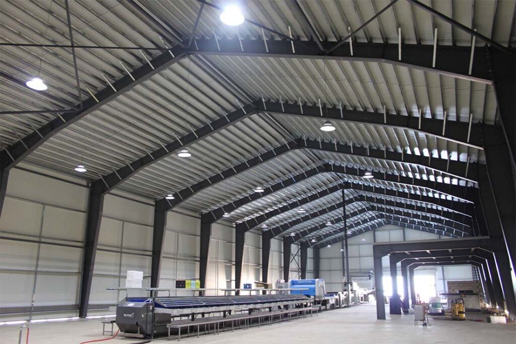 Interior view of a steel workshop building with crane-ready H-beam frames and clear-span structure.