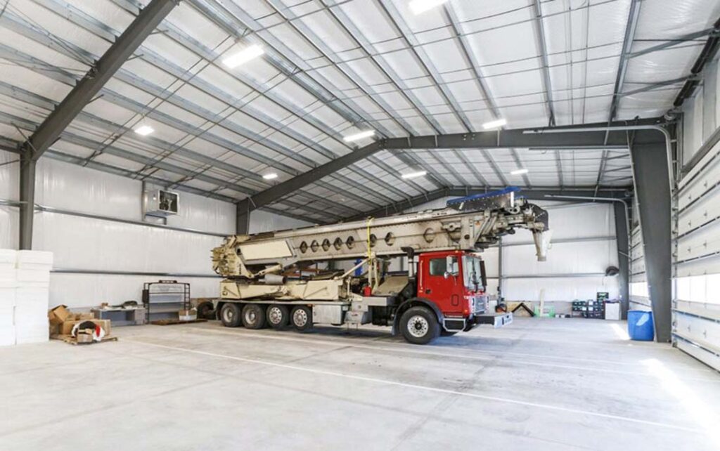 Spacious interior of a prefabricated metal garage featuring a heavy-duty steel frame and large truck parking area, designed and manufactured by Vizsteel.