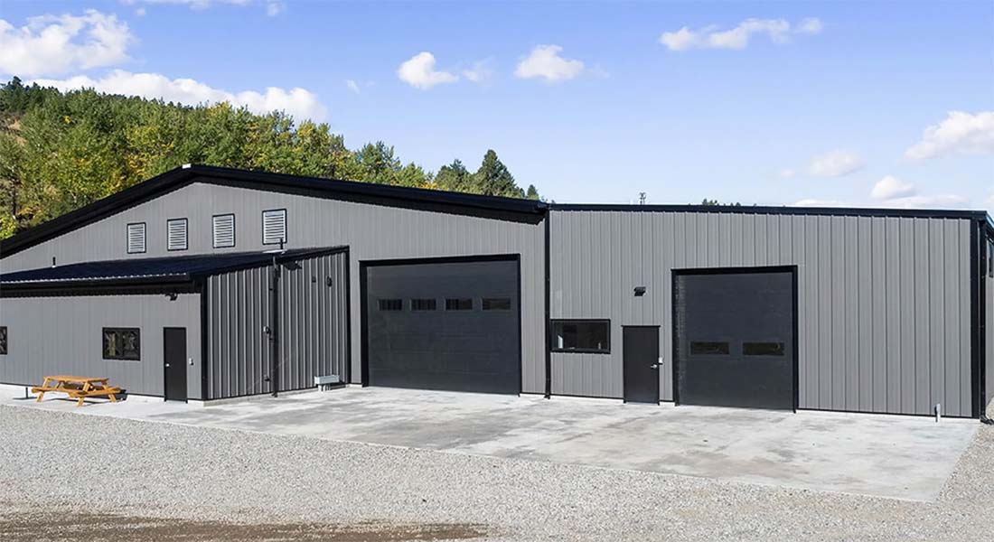Prefabricated metal horse barn building with multiple bay doors, durable steel wall panels, and a low-maintenance exterior