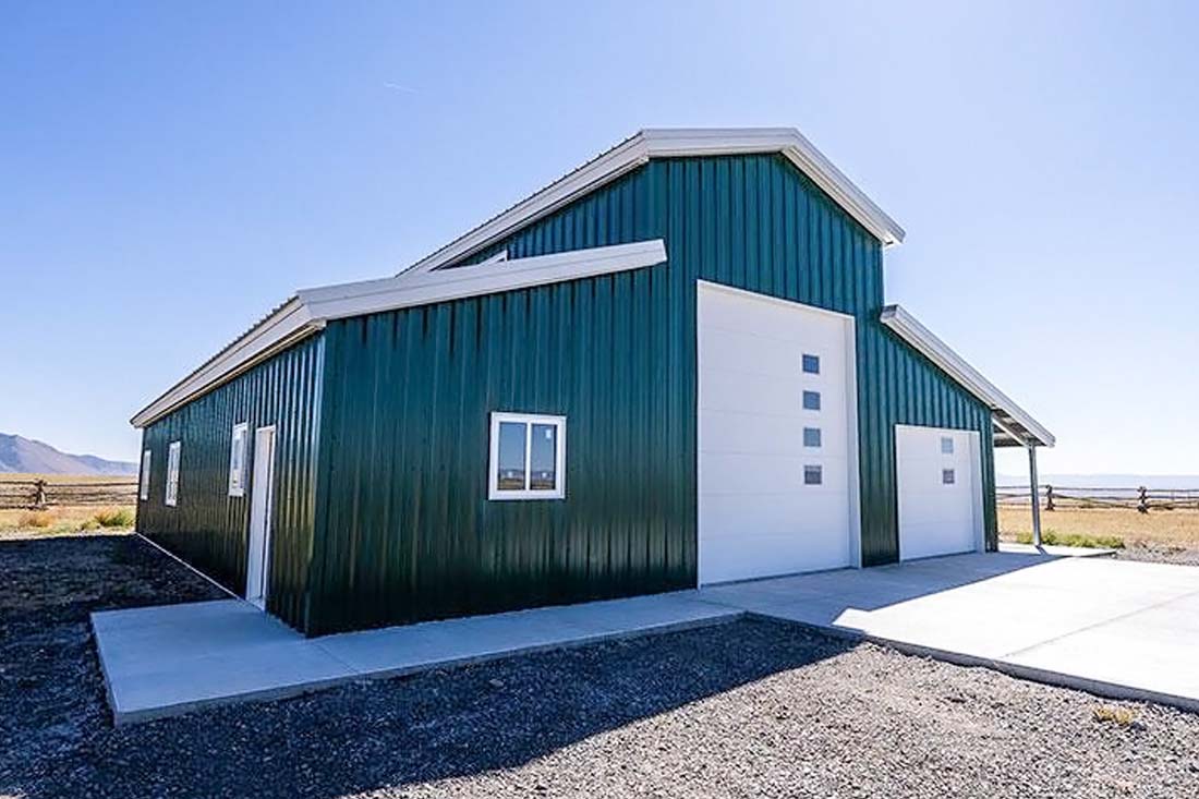 Prefabricated steel barn with gable roof design and wide access doors, suitable for farm equipment storage, utility use, and optional ventilation or insulation upgrades.