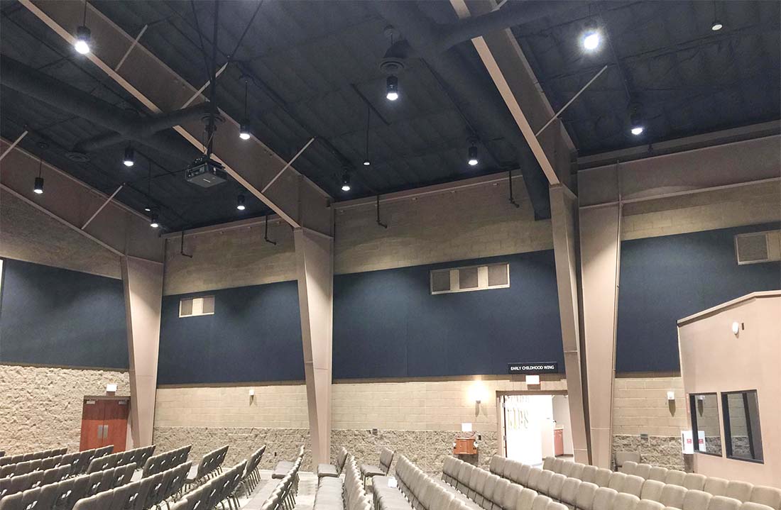 Interior worship hall of a steel church building with high ceiling, lighting, and seating area.