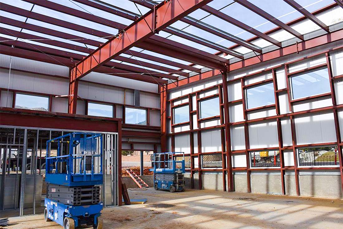 Steel frame structure inside an office building with wall panels and scissor lifts during installation and fit-out.