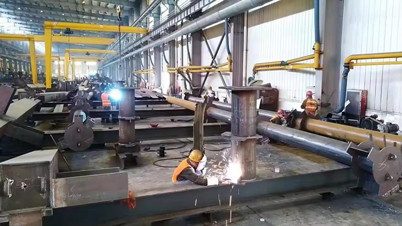 Skilled welders performing manual welding and touch-up work on steel structure components at Vizsteel workshop.