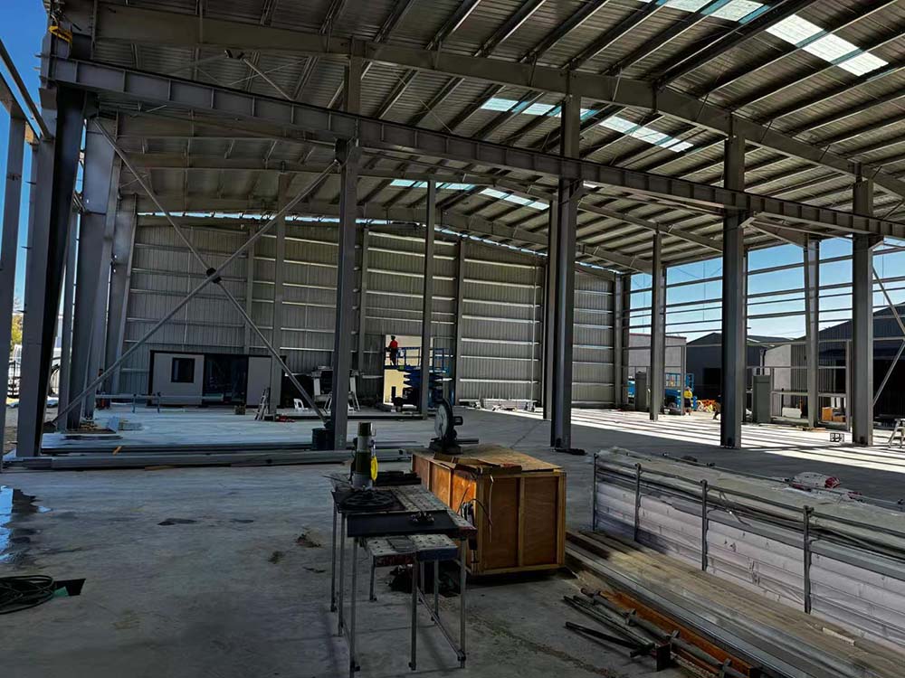 On-site installation progress inside the 25m x 50m x 8m steel workshop, showing columns, beams, and work area.