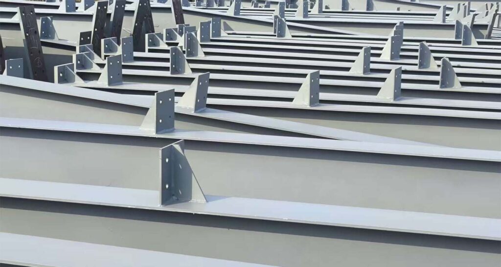 Pre-fabricated steel beams with connection plates stacked in order, ready for delivery and on-site installation in a steel warehouse project.