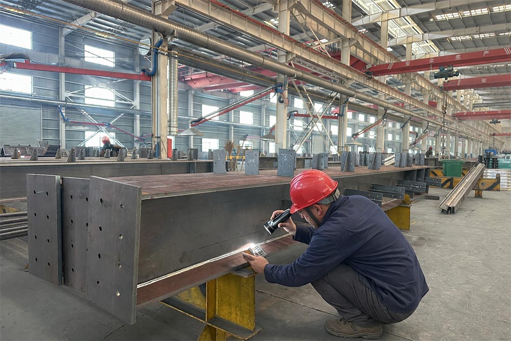 Worker inspecting weld quality on steel component